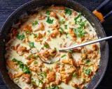 Pfifferlinge in cremiger Rahmsauce, garniert mit Petersilie, in einer Pfanne. Ein Löffel ragt aus der köstlichen Speise.