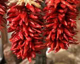 Zwei Stränge getrockneter, leuchtend roter Peperoncini hängen nebeneinander. Diese scharfen Chilischoten, auch Peperoncino genannt, sind ein Muss für Liebhaber würziger Gerichte.