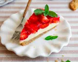 Ein Stück Erdbeerkuchen mit Frischkäsefüllung und glasierten Erdbeeren, garniert mit Minze. Perfekt für einen 5 min kuchen ohne backen.