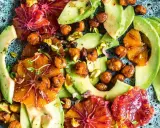 Ein bunter Avocado-Salat mit Blutorangen, Kichererbsen und Pistazien auf einem rustikalen Teller.