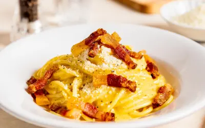 Spaghetti Carbonara mit knuspriger Pancetta, cremigem Ei und Käse bestreut. Ein Klassiker der italienischen Küche.
