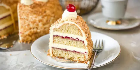 Ein Stück Frankfurter Kranz mit Buttercreme und Kirschen, umhüllt von gehackten Nüssen. Ein Genuss für jeden Kaffeetisch.