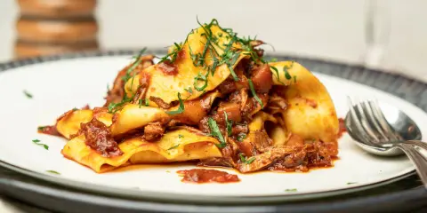 Herzhaftes italienisches Gericht: breite Bandnudeln mit einer reichhaltigen Rindfleischsauce, garniert mit frischen Kräutern.