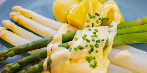 Spargel mit Kartoffeln und cremiger sauce hollandaise, garniert mit Schnittlauch.