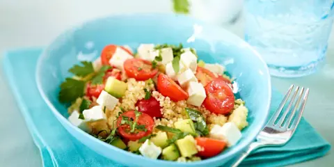Erfrischender Couscous Salat mit Feta, Tomaten und Gurke in einer blauen Schüssel, bereit zum Genießen.