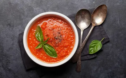 Schüssel mit frischer Tomatensauce, garniert mit Basilikum und Pfeffer. Perfekt, um Tomatensauce selber machen zu lernen.