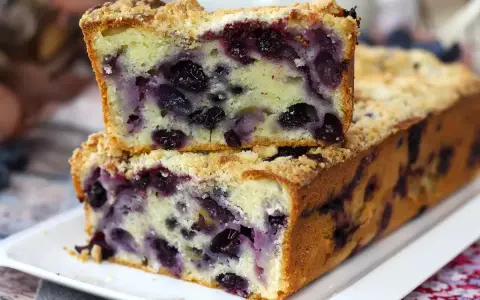 Saftiger Heidelbeerkuchen mit Streuseln, ein Stück gestapelt auf dem ganzen Kuchen.