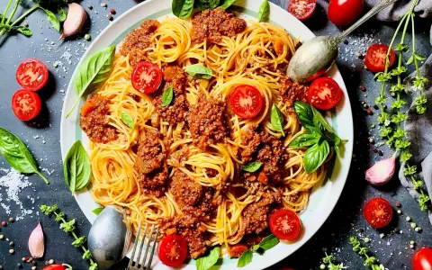 Spaghetti Bolognese mit Hackfleisch, garniert mit frischen Tomaten und Basilikum. Ein Klassiker, bei dem das bolognese welches Fleisch zur Geltung kommt.