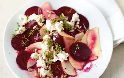 Ein bunter Rote Bete Salat mit Apfelscheiben, zerbröckeltem Käse, Sonnenblumenkernen und Kresse.