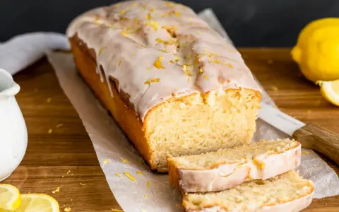 Saftiger veganer Zitronenkuchen mit Zuckerguss und Zitronenschale bestreut. Ein köstlicher Genuss!