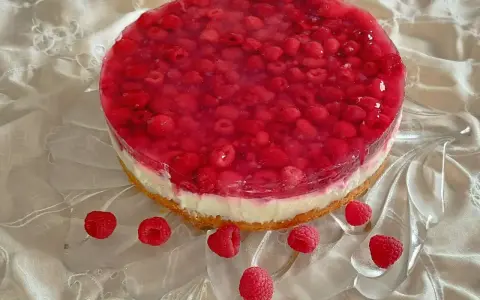Himbeer Joghurt Torte mit frischen Himbeeren und Tortenguss auf einem cremigen Boden, verziert mit einzelnen Himbeeren.