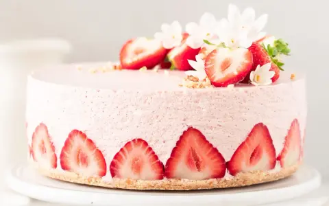 Ein zarter Erdbeer Cheesecake, verziert mit frischen Erdbeerscheiben und Blüten. Dieses Erdbeer Cheesecake Rezept sieht köstlich aus!