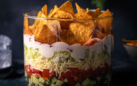 Schichtsalat im Glas: knackiger Salat, Tomaten, Käse, saure Sahne und Tortilla-Chips. Ein leckerer nacho salat.