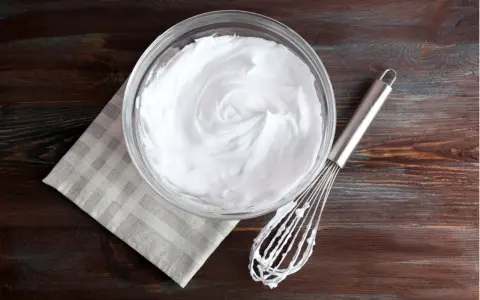 Schneebesen neben Schüssel mit steif geschlagenem Eiweiß. Eine tolle Alternative, wenn man fragt, was kann man statt Sahne nehmen.