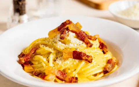 Spaghetti Carbonara mit knuspriger Pancetta, cremigem Ei und Käse bestreut. Ein Klassiker der italienischen Küche.