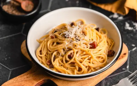 Ein Teller Spaghetti Carbonara, garniert mit Parmesan und schwarzem Pfeffer. Perfekt für authentische Carbonara Rezepte.