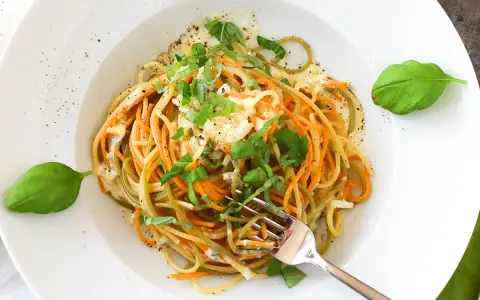 Bunte Spaghetti mit cremiger Gorgonzola-Sauce und frischem Basilikum, garniert mit Pfeffer. Ein Genuss für Augen und Gaumen.