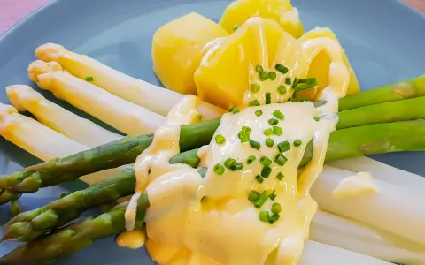 Spargel mit Kartoffeln und cremiger sauce hollandaise, garniert mit Schnittlauch.