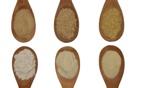 Sechs Holzlöffel mit verschiedenen Mehlsorten: feines, grobes und griffiges Mehl sowie Grieß.