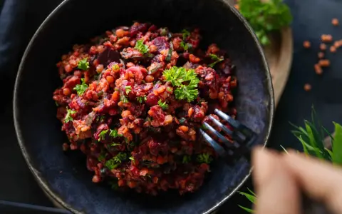 Ein köstlicher rote Linsen Salat mit Roter Bete und frischer Petersilie, serviert in einer dunklen Schüssel.
