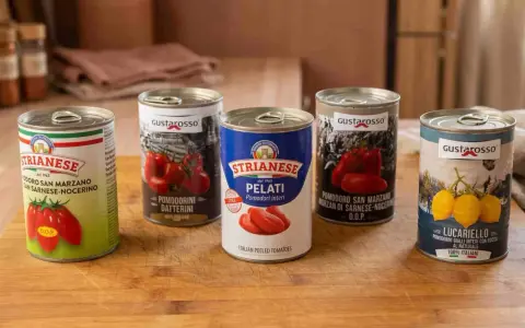 Fünf Dosen mit verschiedenen Tomatenprodukten für Pizza, darunter ganze, geschälte und Datterini-Tomaten.