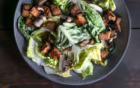 Herzhafter Caesar Salad mit knackigem Römersalat, gerösteten Croutons und Pilzen, übergossen mit cremiger Sauce.