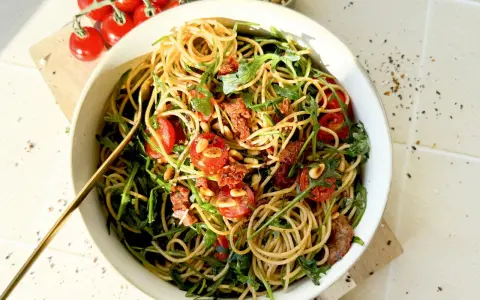 Mediterraner Salat mit getrockneten Tomaten und Rucola, garniert mit Pinienkernen. Ein köstliches Gericht, das nach Sommer schmeckt.