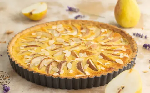 Eine köstliche Birnen Tarte mit Mandelsplittern, garniert mit Lavendel und frischen Birnenstücken.