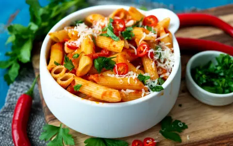 Eine Schüssel Penne all'Arrabbiata, garniert mit frischer Petersilie und Chilischeiben.