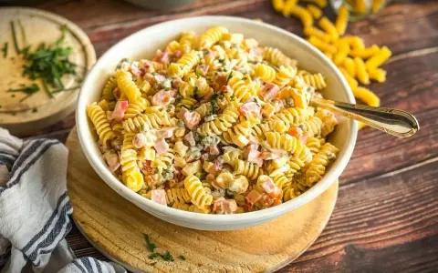 Schüssel mit cremigem Nudelsalat, gefüllt mit Schinken, Erbsen und Kräutern. Der beste Nudelsalat für jede Gelegenheit!