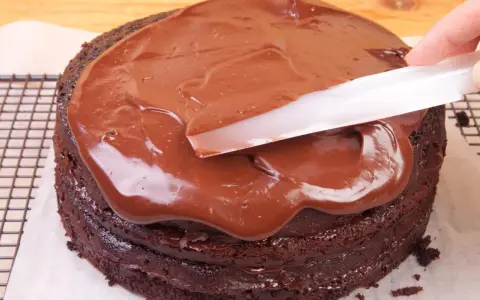 Schokoladenkuchen wird mit glatter, glänzender Ganache überzogen. Was ist eine Ganache? Eine köstliche Mischung aus Schokolade und Sahne.