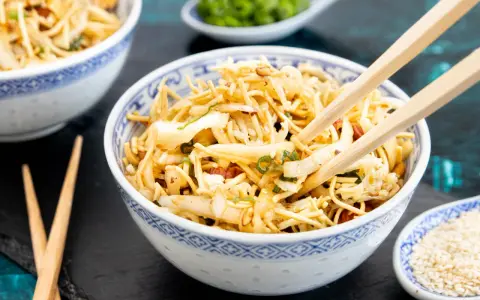 Ein Schüsselchen "friss dich dumm Salat" mit Nudeln, Gemüse und Erdnüssen, bereit zum Genießen mit Stäbchen.