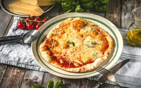 Eine köstliche Pizza Quattro Formaggi mit vier Käsesorten, serviert mit frischen Tomaten und Basilikum auf einem Holztisch.
