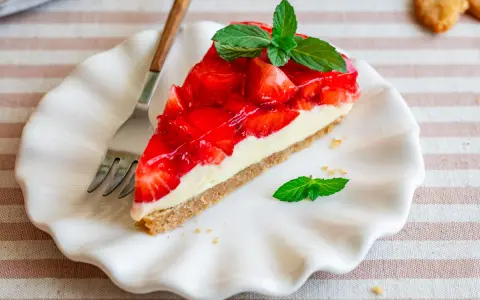 Ein Stück Erdbeerkuchen mit Frischkäsefüllung und glasierten Erdbeeren, garniert mit Minze. Perfekt für einen 5 min kuchen ohne backen.