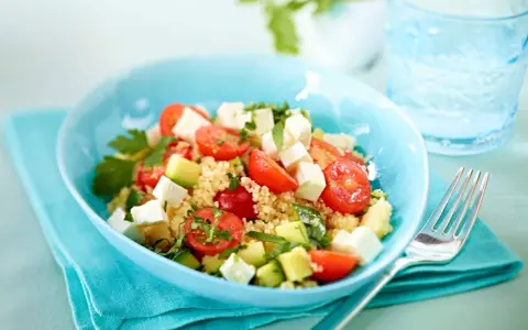 Erfrischender Couscous Salat mit Feta, Tomaten und Gurke in einer blauen Schüssel, bereit zum Genießen.