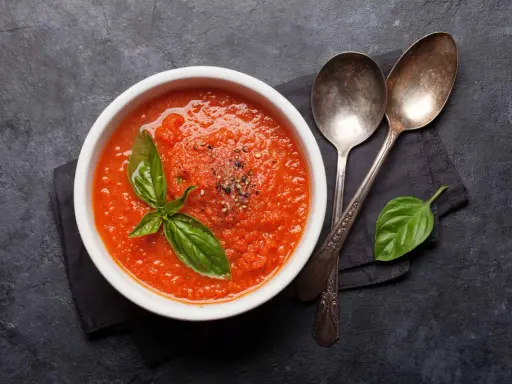 Schüssel mit frischer Tomatensauce, garniert mit Basilikum und Pfeffer. Perfekt, um Tomatensauce selber machen zu lernen.