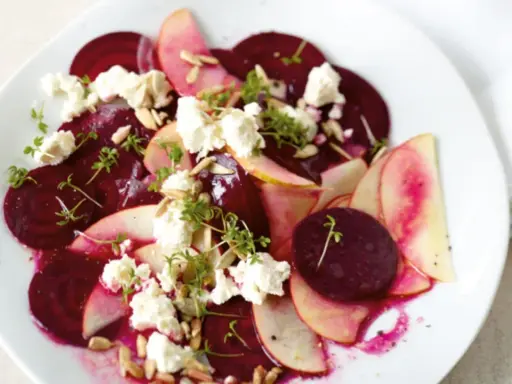 Ein bunter Rote Bete Salat mit Apfelscheiben, zerbröckeltem Käse, Sonnenblumenkernen und Kresse.