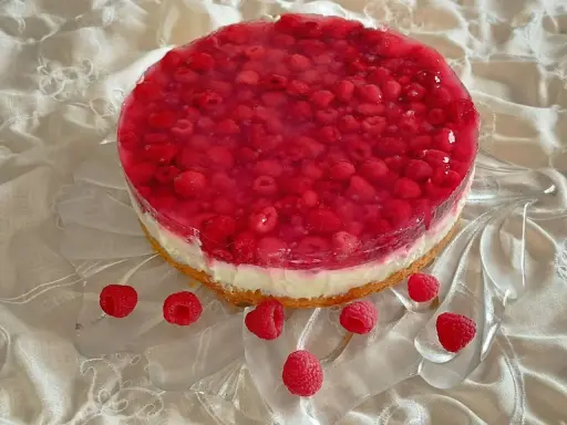 Himbeer Joghurt Torte mit frischen Himbeeren und Tortenguss auf einem cremigen Boden, verziert mit einzelnen Himbeeren.