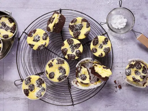 Zupfkuchen Muffins mit Puderzucker bestäubt, auf einem Gitter und in einer Dose.