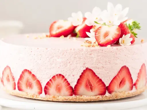 Ein zarter Erdbeer Cheesecake, verziert mit frischen Erdbeerscheiben und Blüten. Dieses Erdbeer Cheesecake Rezept sieht köstlich aus!
