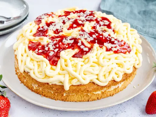 Eine Spaghettieis Torte mit Erdbeersoße und weißen Schokostückchen, die an Spaghetti erinnert.