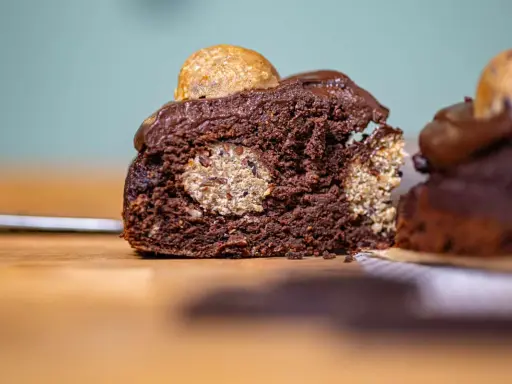 Saftiger Schokoladenkuchen mit versteckten Cookie Dough Kugeln und einem Topping aus Schokoladenglasur und einer weiteren Cookie Dough Kugel.