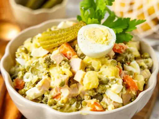 Ein köstlicher Olivier Salat, garniert mit Ei und Gurke, bereit zum Genießen.