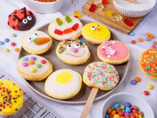Bunte Kekse mit Zuckerguss, inspiriert von einem amerikanischen Rezept: Marienkäfer, Küken, Karotten und Gesichter.