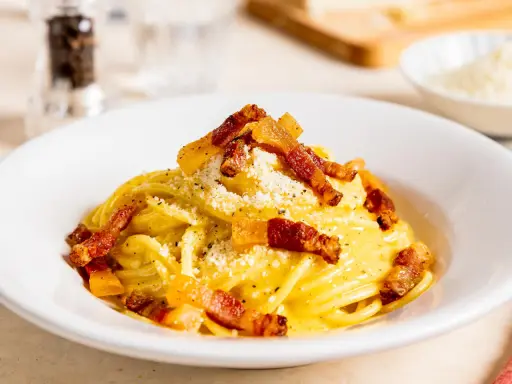 Spaghetti Carbonara mit knuspriger Pancetta, cremigem Ei und Käse bestreut. Ein Klassiker der italienischen Küche.