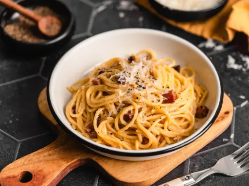 Ein Teller Spaghetti Carbonara, garniert mit Parmesan und schwarzem Pfeffer. Perfekt für authentische Carbonara Rezepte.