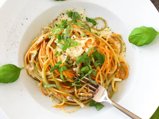 Bunte Spaghetti mit cremiger Gorgonzola-Sauce und frischem Basilikum, garniert mit Pfeffer. Ein Genuss für Augen und Gaumen.