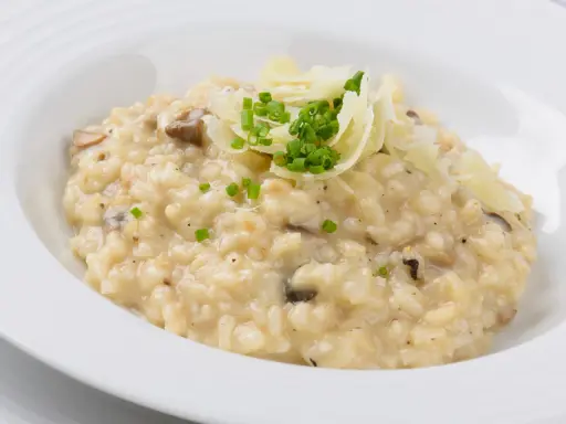 Cremiger Pilz-Risotto-Reis, garniert mit Parmesan und Schnittlauch, serviert in einer weißen Schüssel.