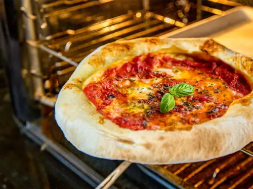 Eine köstliche Pizza mit geschmolzenem Käse und frischem Basilikum wird im Backofen gebacken.
