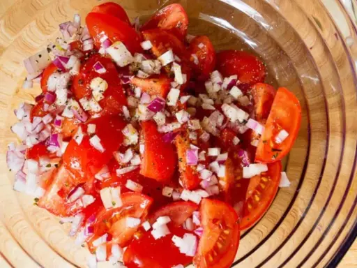 Frischer Tomatensalat mit roten Zwiebeln und Kräutern, bereit für Feta.